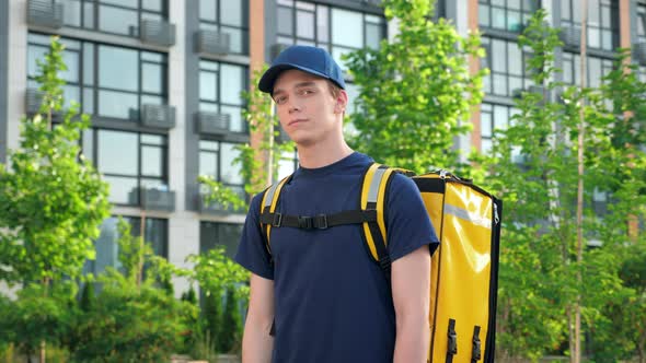 Portrait Man Courier Food Delivery with Thermal Backpack Turns Head Looks Camera