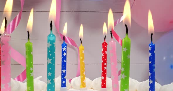 Birthday cake with candles on the background of balloons.