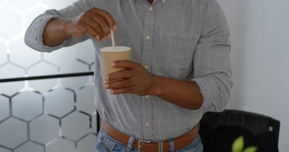 Businessman stirring coffee at office 