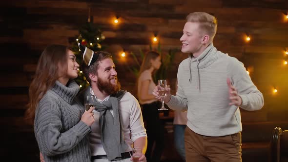 Young Man Clinking Champagne Glasses with Couple in Celebrating New Years Party