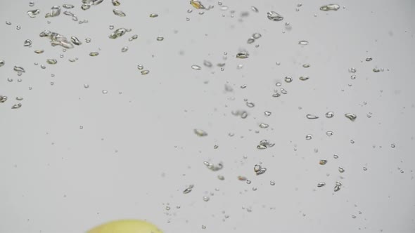 Tasty Fruits Red and Yellow Pear Falling Into Water with Splash and Air Bubbles White Background