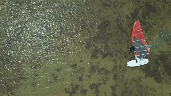 Aerial View Surfer Who Goes in Shallow Water and Drags a Windsurf Board with a Sail