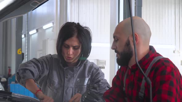 Two Professional Mechanics Female and Male Repairing a Car in Car Repair Shop. Car Service, Repair