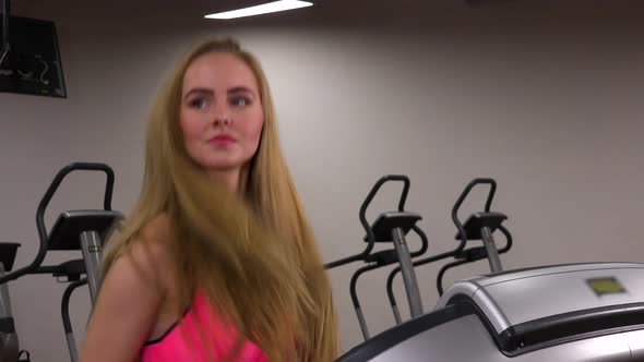 A Young Beautiful Woman Runs on a Treadmill in a Gym - Closeup