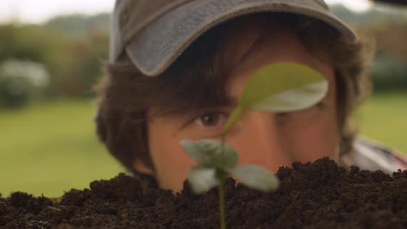 Portrait of a Farmer Looking at a Seedling