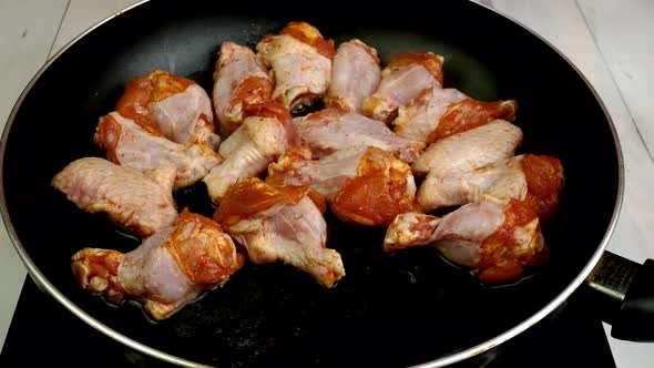 Chef Places Many Sprinkled with Spices Sliced Chicken Wings in Hot Frying Pan for Preparation