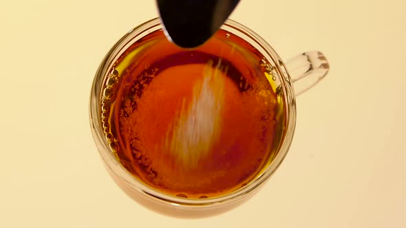 Sugar Fill Into Cup of Black Tea. View From Above