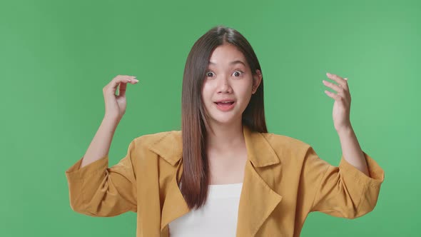 Young Asian Woman Opening Her Eyes With Palms , Surprised And Saying Wow In The Green Screen Studio