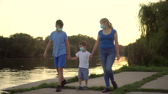 A Family with a Child in Medical Masks Walk Near the Lake