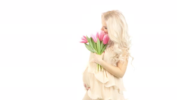 Beautiful Young Pregnant Woman Dressed in a Pink Dress with Tulips, White