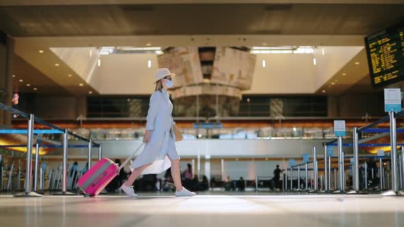 Slow Motion of Stylish Woman in Mask with Travel Bag in Empty Airport Terminal