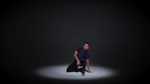 Man Is Dancing Breakdance on the Dark Background in Simple Grey T-shirt and Grey Jeans