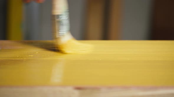 Painting Wood with Yellow Paint Using Brush Closeup