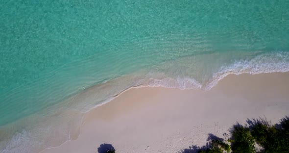 Natural fly over abstract shot of a white sandy paradise beach and blue sea background in vibrant 4K