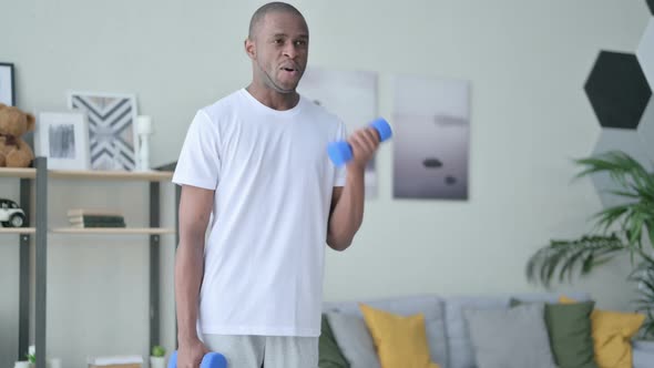 Sporty African Man Working Out with Dumbbells at Home