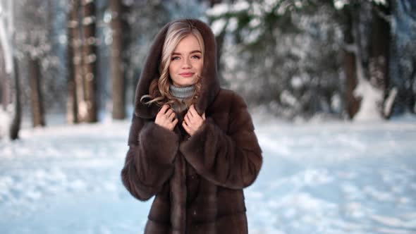 Playful Woman in Hood Fur Coat Smiling Walking at Winter Nature Forest