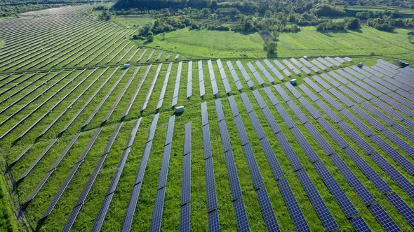 Aerial view on Solar Power Station in Green Field near River at Sunny Day. Fly over Solar Farm.