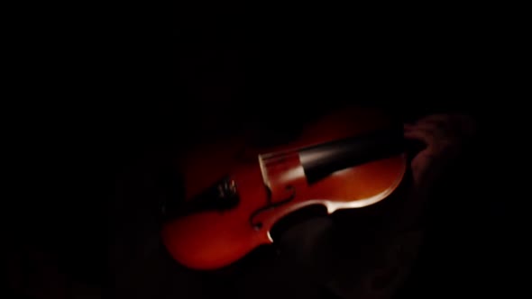 Woman in a white blouse emerges from the darkness and taking the violin begins to play classical