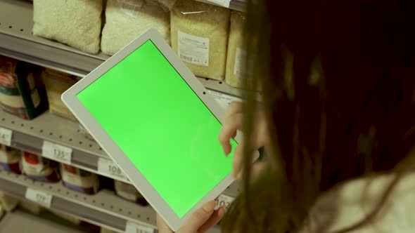 Closeup of a Young Woman's Hand Holding a Tablet Computer with a Green Screen Layout