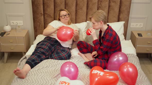 Two Beautiful Women Lgbt Couple Lie in Bed and Inflate Balloons Fool Around and Have Fun