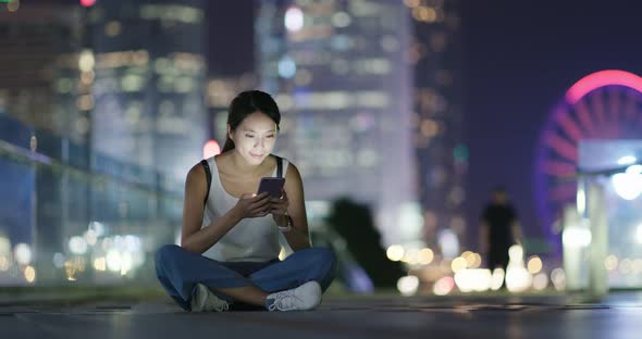 Woman use of mobile phone in city at night