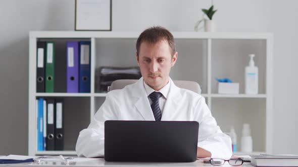 Professional medical doctor working in hospital office using computer technology.