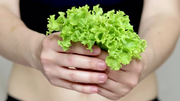 weight loss and healthy nutrition concept. fit woman is holding in hand green lettuce salad leaves. 