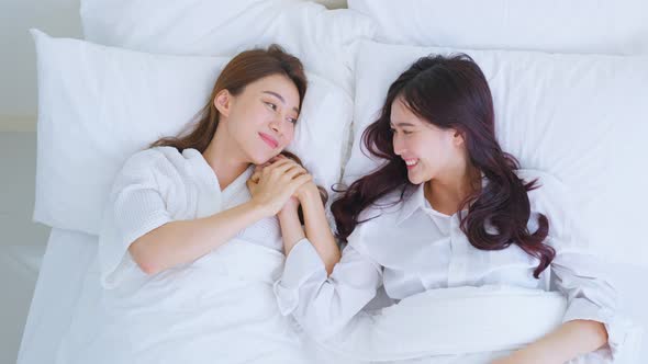 Asian lesbian woman couple lying down on bed and hold hand each other. Homosexual-LGBTQ concept.