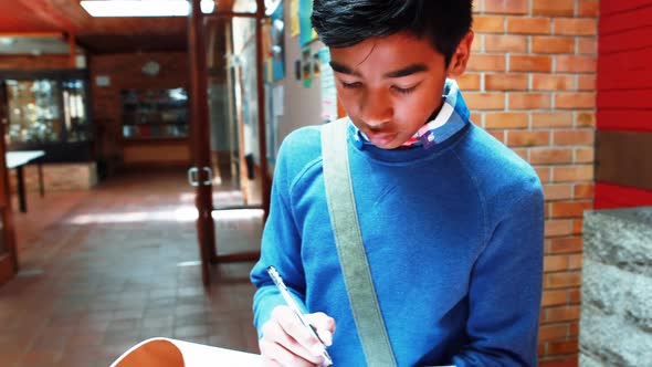 Schoolboy witting while walking in corridor