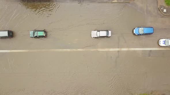 Aerial view of traffic cars driving on flooded road with rain water.