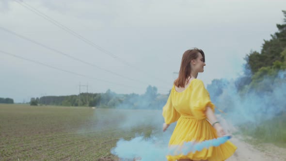 Smiling Woman Whirling in Color Smoke Among Field