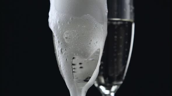 Champagne Pouring From Bottle Into Two Glasses on Black Background. Close Up