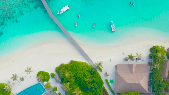 Aerial top view of resort with palms at the beach and turquoise Indian ocean, Maldives