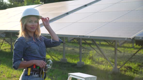 Female Engineer in a White Helmet Is at the Solar Power Station. The Green Energy Concept