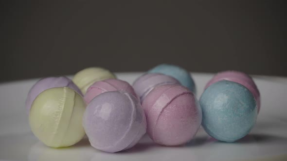 Bath Bombs in Different Colors Spin Against a Black Background