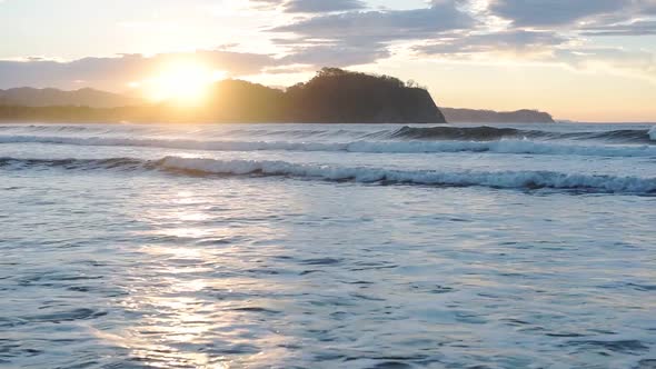 Ocean waves crashing on Costa Rica coastline of beach Playa Buena Vista, during sunset