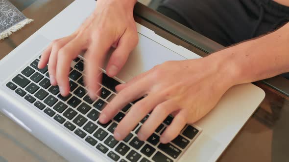 Typing on metal laptop keyboard and using trackpad.