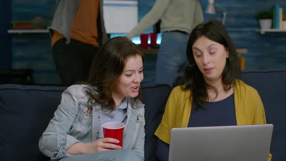 Excited Friends Watching Entertainment Show on Laptop While Sitting on Couch