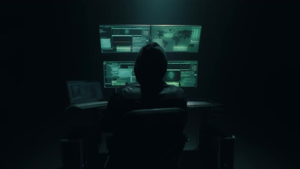 Anonymous Hacker Using Computer in Dark Room