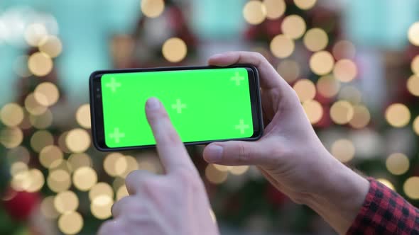 Hands Of Young Man Using Phone Against Illuminated Christmas Trees Outdoors