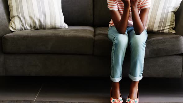 Upset girl sitting on sofa in corridor