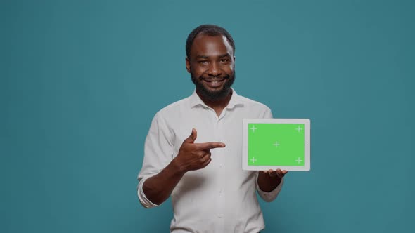 Happy Man Pointing at Digital Tablet with Horizontal Green Screen
