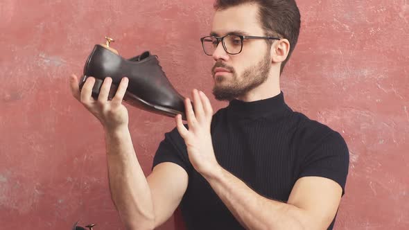 Young Awesome Shoemaker with Glasses Looking for Defects in Man's Hands