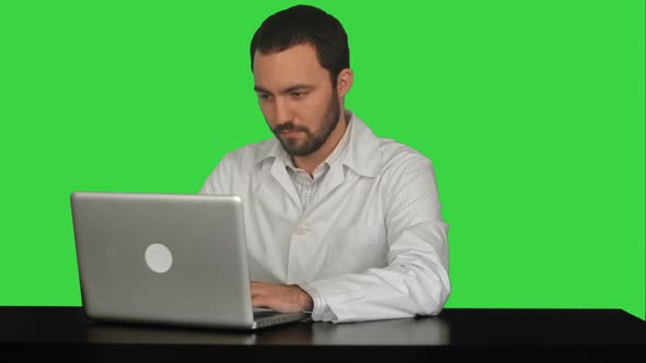 Young Doctor Thinking Idea with Laptop Computer on the Table on a Green Screen, Chroma Key