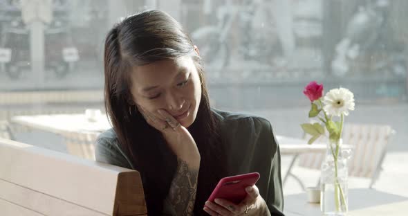 Woman sitting in cafe using her smartphone