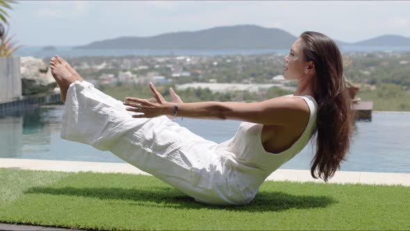 Calm Tourist Practicing Yoga in Balancing Asana Poolside Against Town on Coast