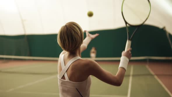 Backside Footage of an Active Female Tennis Player Hitting the Ball with Racket at Tennis Court