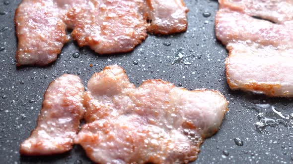 Crispy Pieces of Delicious Bacon are Fried in a Hot Pan