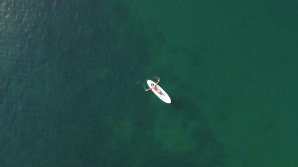 Aerial Drone View on Well Looking Middle Aged Woman with Black Hair in Red Swimsuit Swimming on Sup