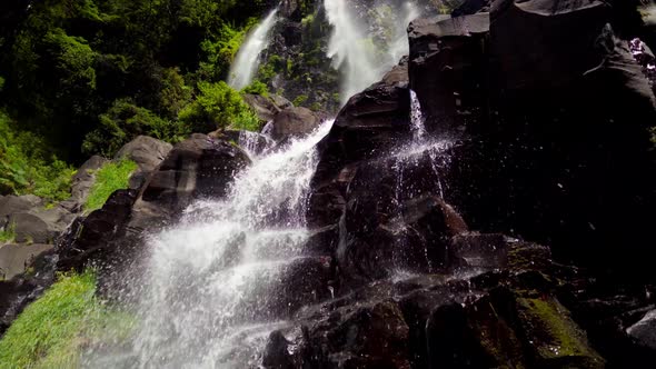 Handheld of Niña Encantada waterfall streaming down rocks surrounded by green dense rainforest at da